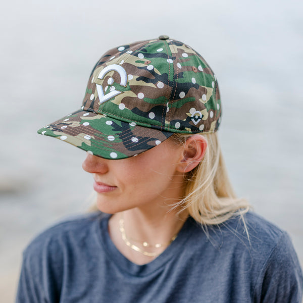 Outsider camo hat with white dots and embroidered logo modeled on a woman