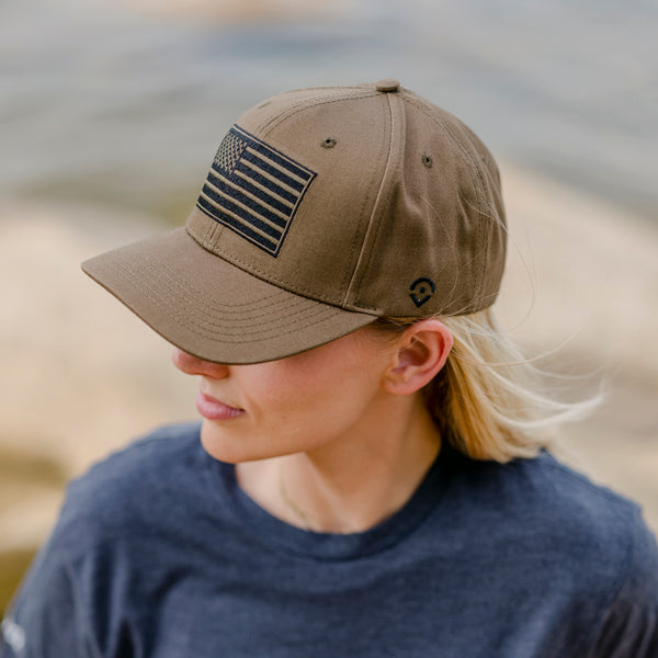 Desert Sand Tan Hat with blacked out black and tan American flag on the front modeled on woman